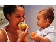 Photo of a woman and child eating fruit.